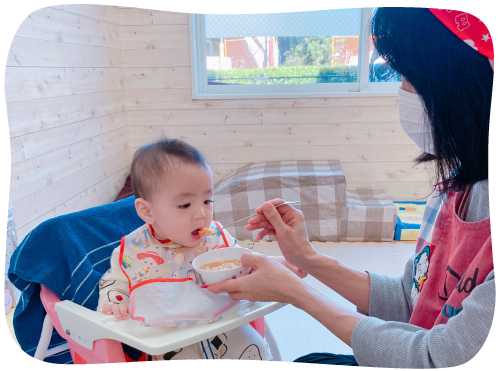 赤ちゃんにご飯を食べさせる保育士